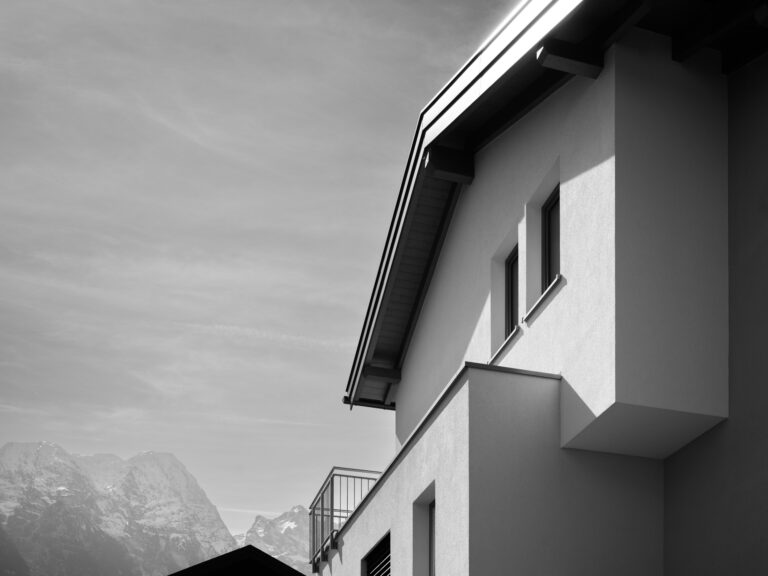 Schwarz-Weiß-Aufnahme eines modernen Hauses mit Blick auf bergige Landschaft im Hintergrund