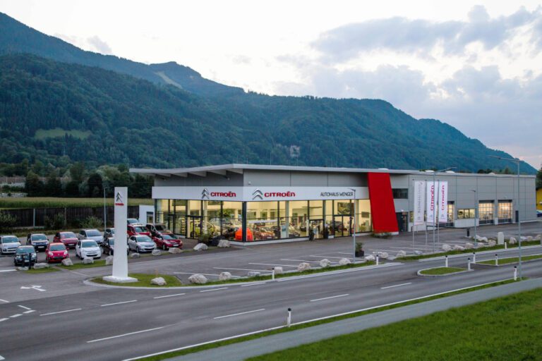 Citroën Autohaus mit Fahrzeugen im Vordergrund und einem bewaldeten Berg im Hintergrund bei Dämmerung