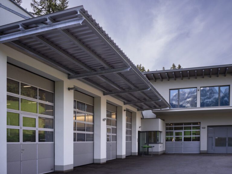 Modernes Schulgebäude mit reflektierenden Glasfenstern und Bergpanorama im Hintergrund