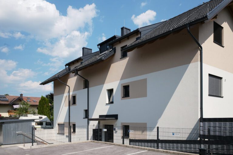 Moderne Mehrfamilienhäuser mit geometrischer Fassadengestaltung unter blauem Himmel