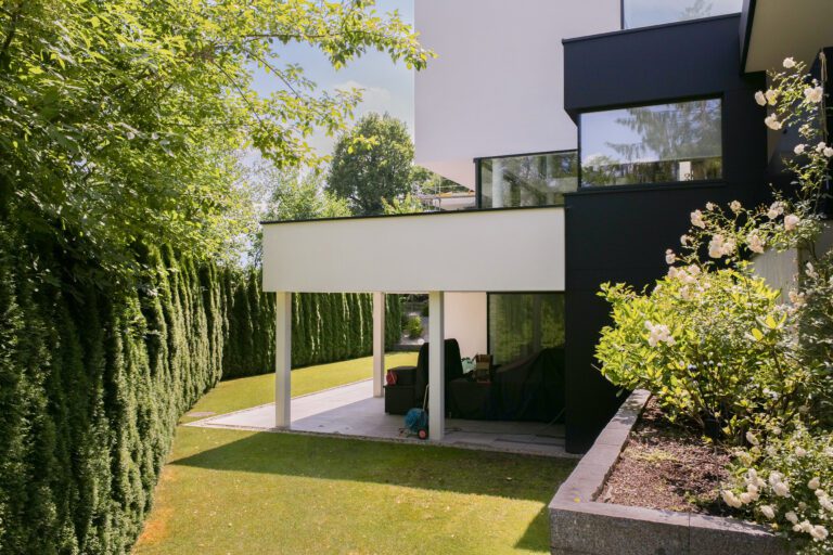 Modernes Haus mit großer Glasfront umgeben von einem gepflegten Garten