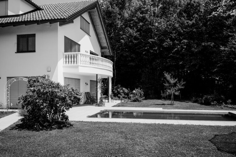 Eine Schwarz-Weiß-Aufnahme eines modernen Hauses mit Balkon, Pool und umgebendem Garten