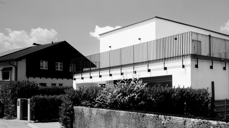 Schwarz-Weiß-Aufnahme zweier benachbarter Gebäude mit unterschiedlichen Architekturstilen