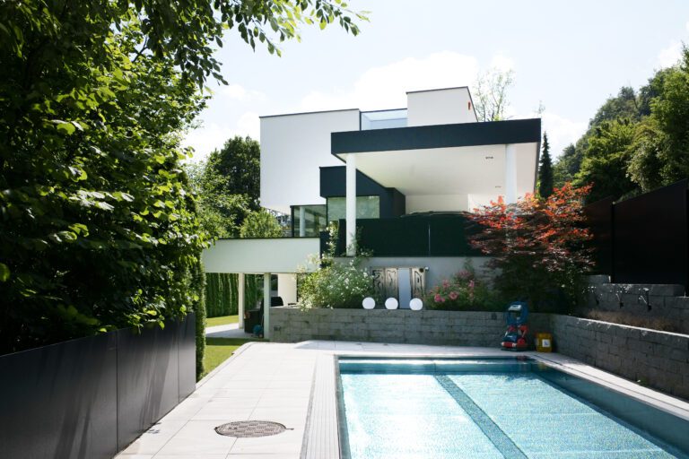 Moderne Villa mit Pool und mehreren Ebenen, umgeben von Bäumen und Sträuchern