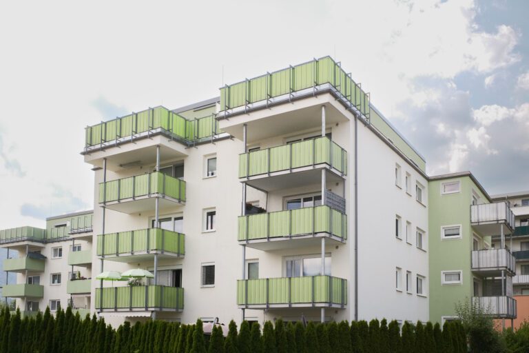 Mehrfamilienhaus mit Balkonen und grünen Markisen